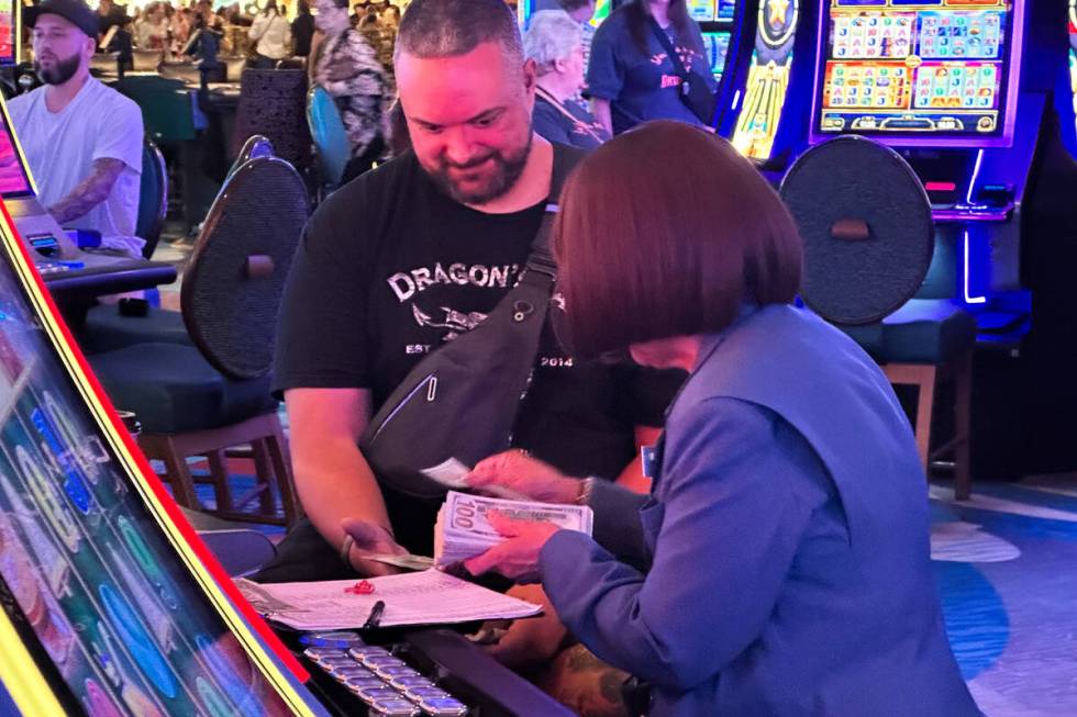 An employee at Bellagio pays out a guest in cash after they win at a slot machine on Saturday, ...