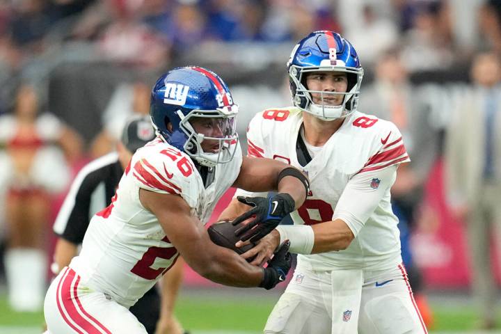 New York Giants quarterback Daniel Jones (8) hands the ball off to Giants running back Saquon B ...