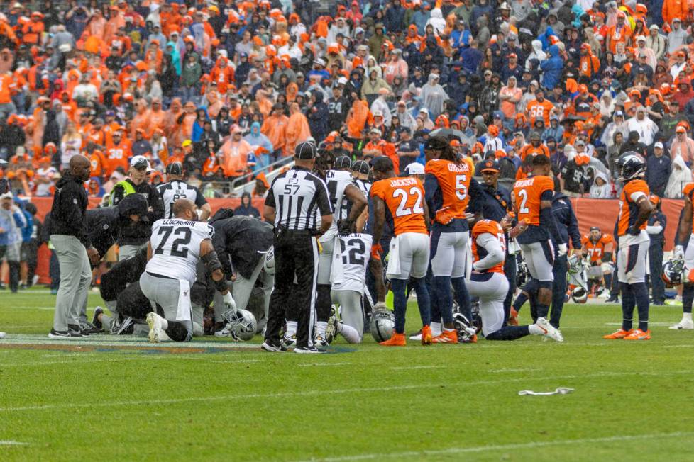 The Raiders and Denver Broncos gather around as Raiders wide receiver Jakobi Meyers (16) lays u ...