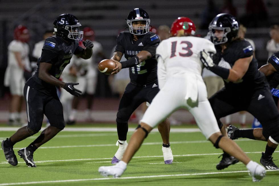 Desert Pines quarterback AJ Stowers (12) hands the ball off to running back Greg Burrell (5) du ...