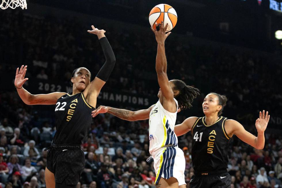 Dallas Wings guard Crystal Dangerfield, center, shoots against Las Vegas Aces forward A'ja Wils ...