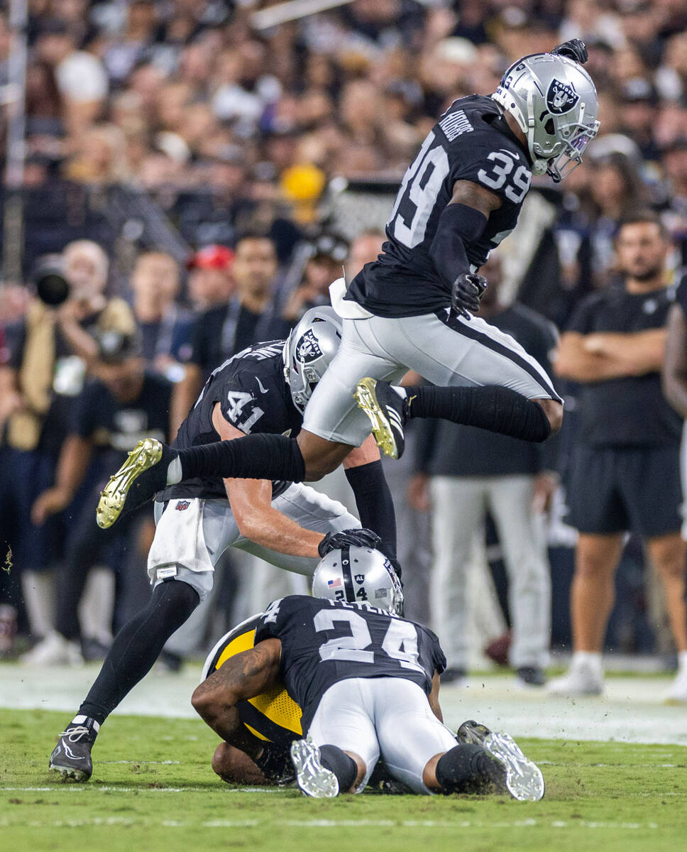 Raiders cornerback Nate Hobbs (39) leaps over teammate cornerback Marcus Peters (24) on a tack ...