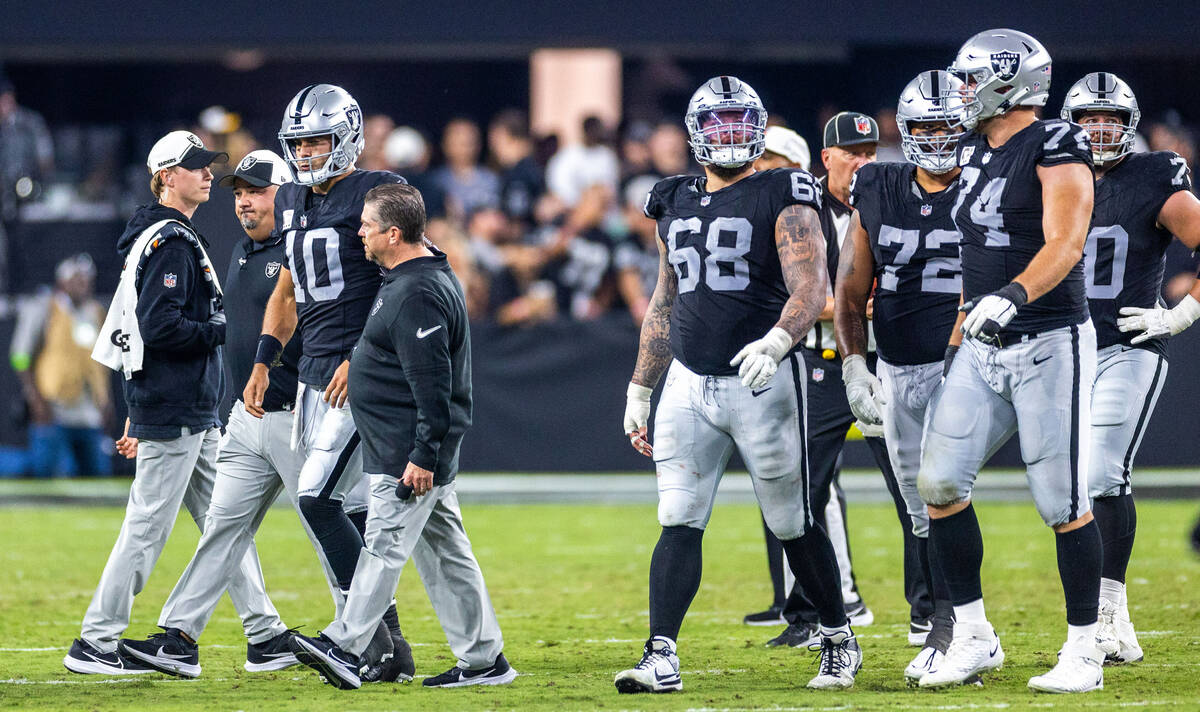 Raiders quarterback Jimmy Garoppolo (10) escorted by medical trainers after being bent back on ...