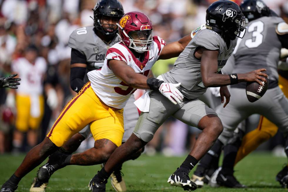 Southern California linebacker Theo Bravos, left, pursues Colorado quarterback Shedeur Sanders ...