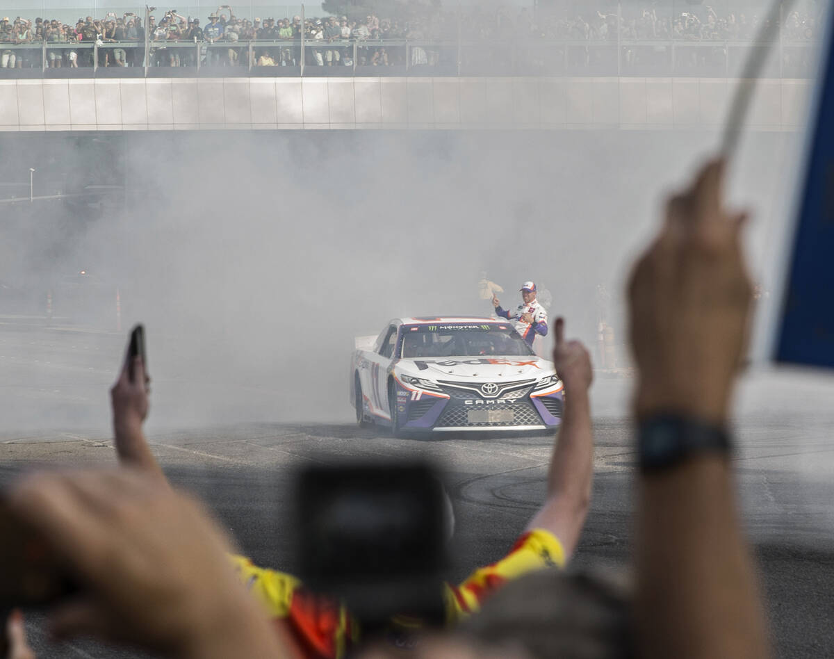 Denny Hamlin waves to fans after doing a burnout at the intersection of East Sands Avenue and S ...