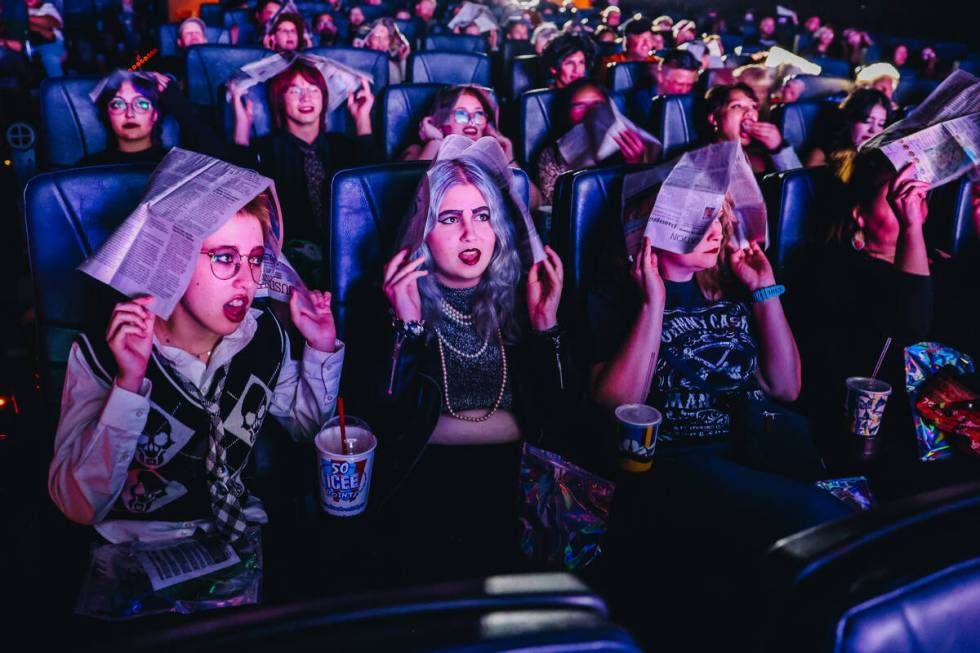 Audience members cover their heads with newspapers to shield themselves from imaginary rain dur ...