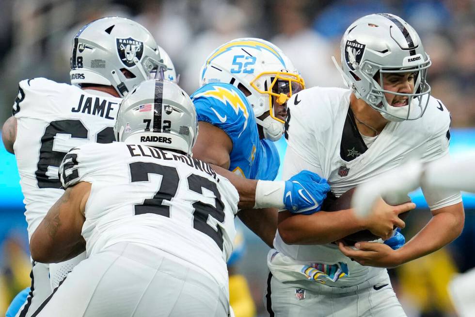Las Vegas Raiders quarterback Aidan O'Connell, right, is sacked by Los Angeles Chargers linebac ...
