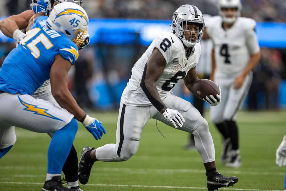 Raiders running back Josh Jacobs (8) looks for room to run as Los Angeles Chargers linebacker T ...
