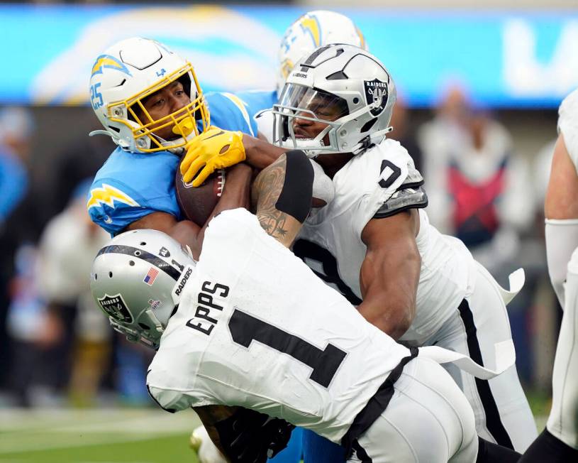 Los Angeles Chargers running back Joshua Kelley, left, is tackled by Las Vegas Raiders safety M ...