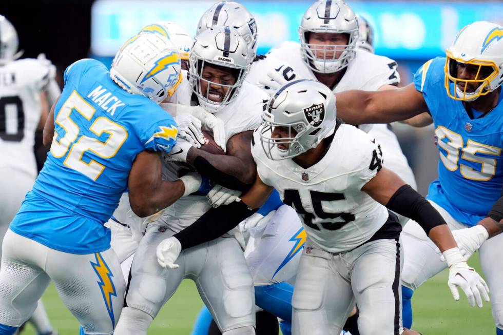 Las Vegas Raiders running back Josh Jacobs, center, is tackled by Los Angeles Chargers lineback ...