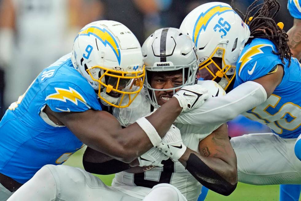 Las Vegas Raiders running back Josh Jacobs, center, is tackled by Los Angeles Chargers lineback ...