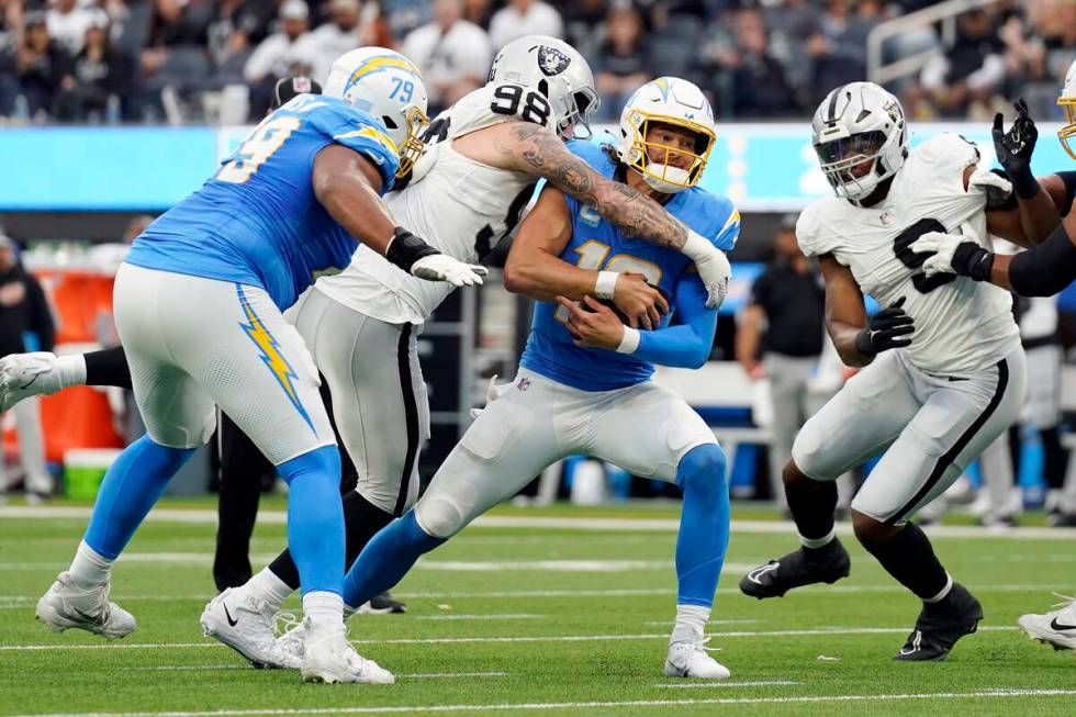 Los Angeles Chargers quarterback Justin Herbert, center, is sacked by Las Vegas Raiders defensi ...