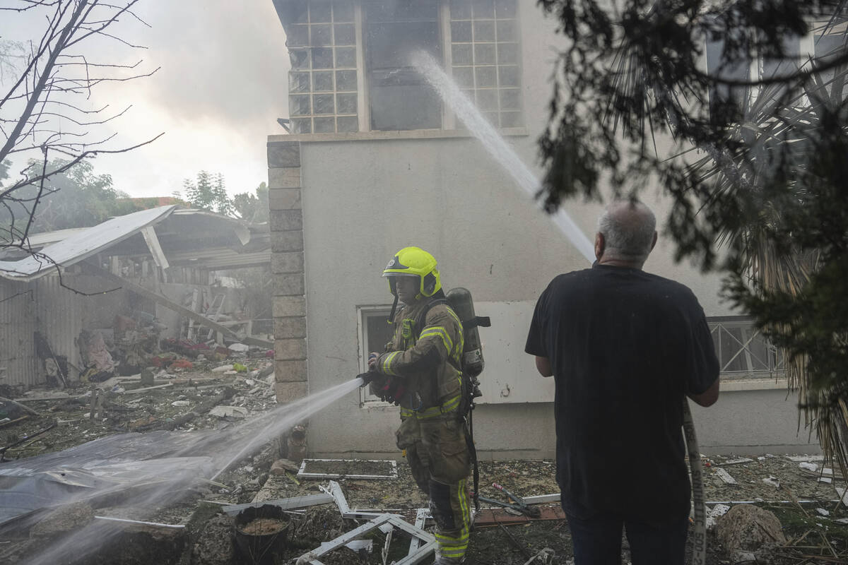 Israeli firefighters extinguish fire after a rocket fired from the Gaza Strip hit a house in As ...