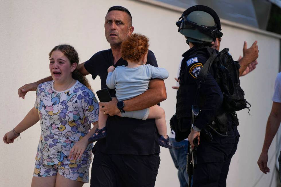 Israeli police officers evacuate a family from a site hit by a rocket fired from the Gaza Strip ...