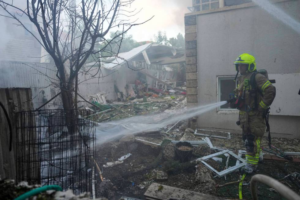 Israeli firefighters extinguish fire after a rocket fired from the Gaza Strip hit a house in As ...