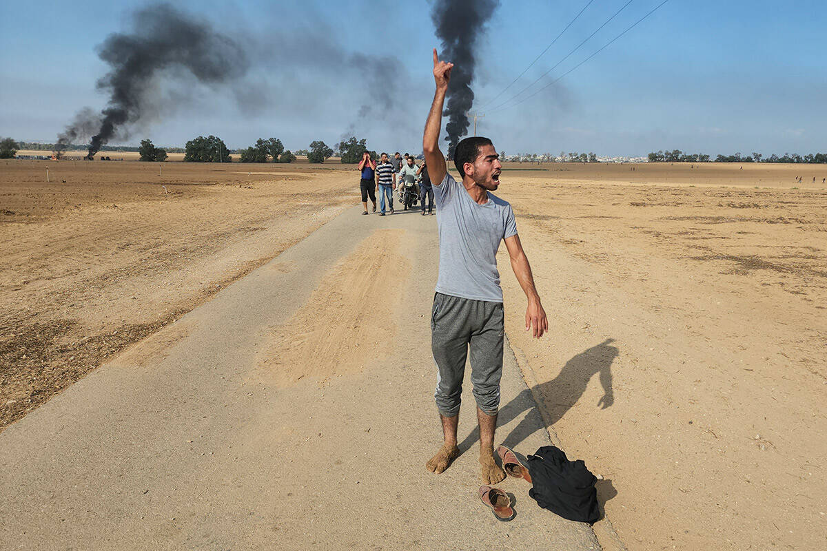 Palestinians walk away from the kibbutz of Kfar Azza, Israel, near the fence with the Gaza stri ...