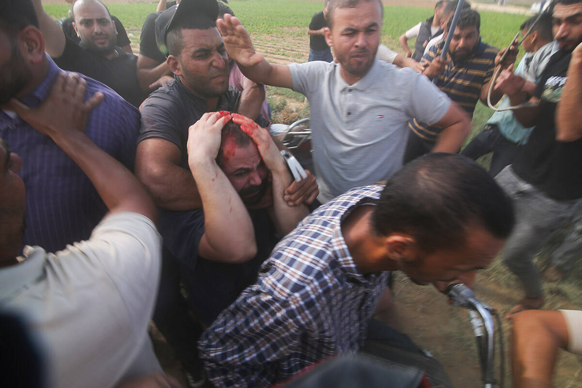 Palestinians transport a captured Israeli civilian, center, from Kibbutz Kfar Azza into the Gaz ...