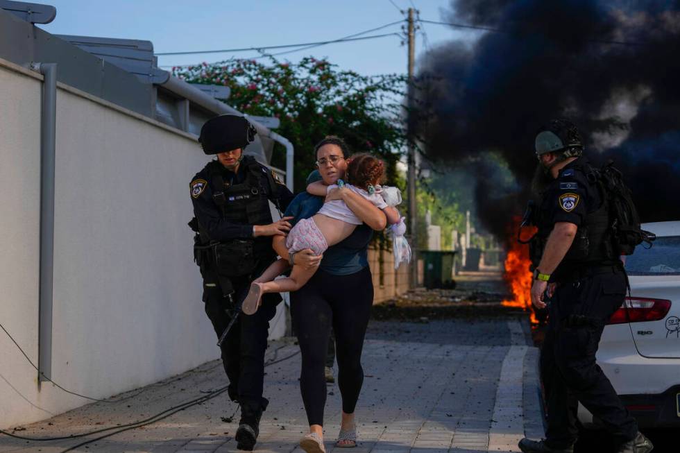 Israeli police officers evacuate a woman and a child from a site hit by a rocket fired from the ...