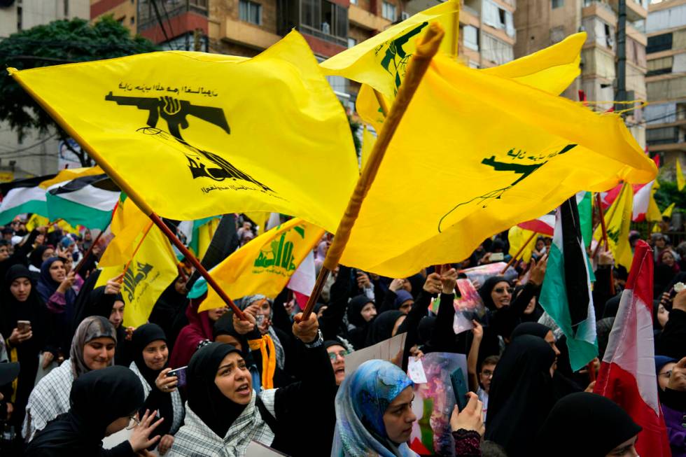 Hezbollah supporters wave the group's flag, as well as those of Palestinian and Lebanon during ...