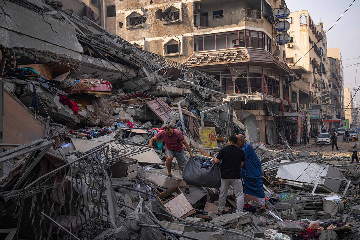 Palestinians scour the debris from the rubble of a building after it was struck by an Israeli a ...