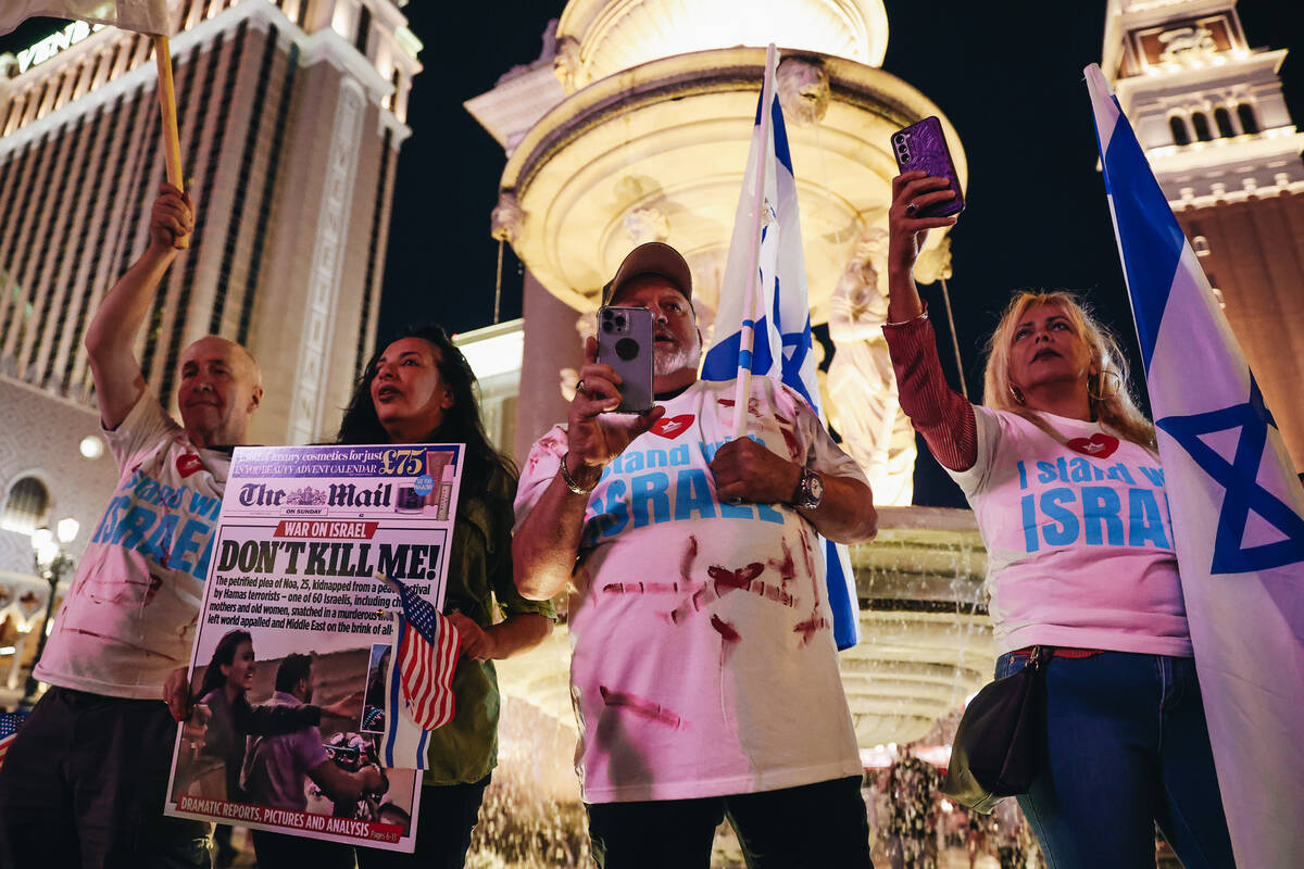 Supporters hold up signs during a pro-Israel rally outside the Venetian on Sunday, Oct. 8, 2023 ...