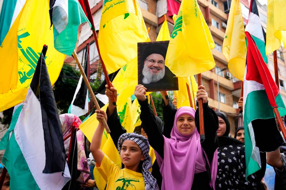 A Hezbollah supporter holds up a portrait of Hezbollah leader Sayyed Hassan Nasrallah as others ...