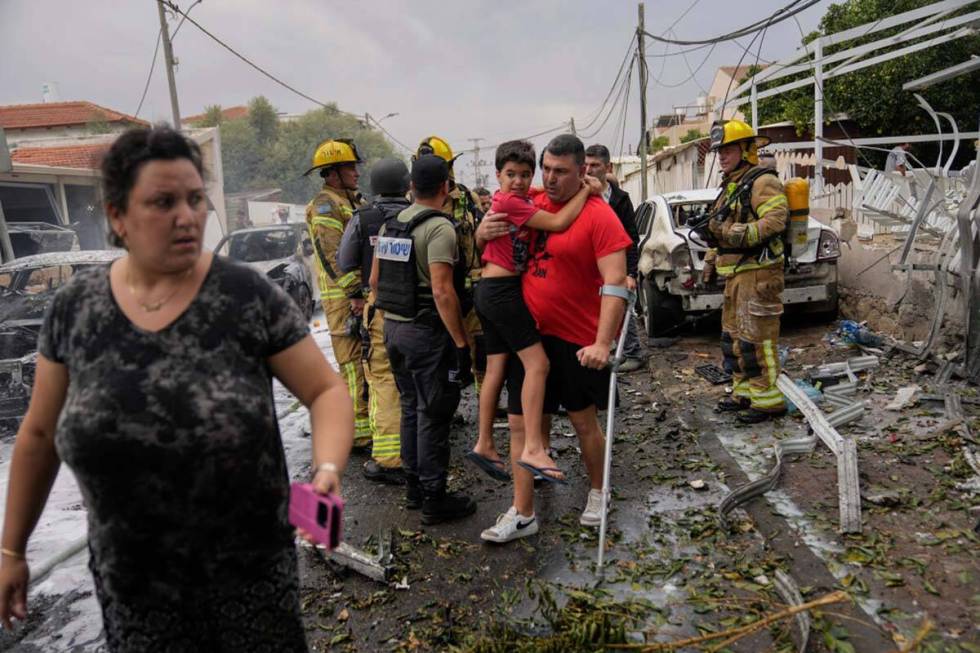 Israelis evacuate a site struck by a rocket fired from the Gaza Strip in Ashkelon, Israel, Mond ...