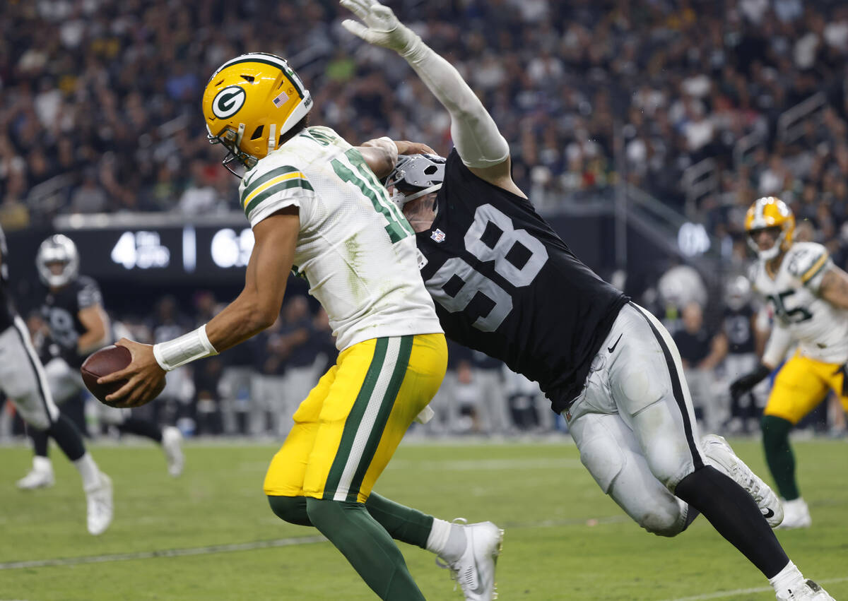 Green Bay Packers quarterback Jordan Love (10) tries to avoid a tackle from Raiders defensive e ...