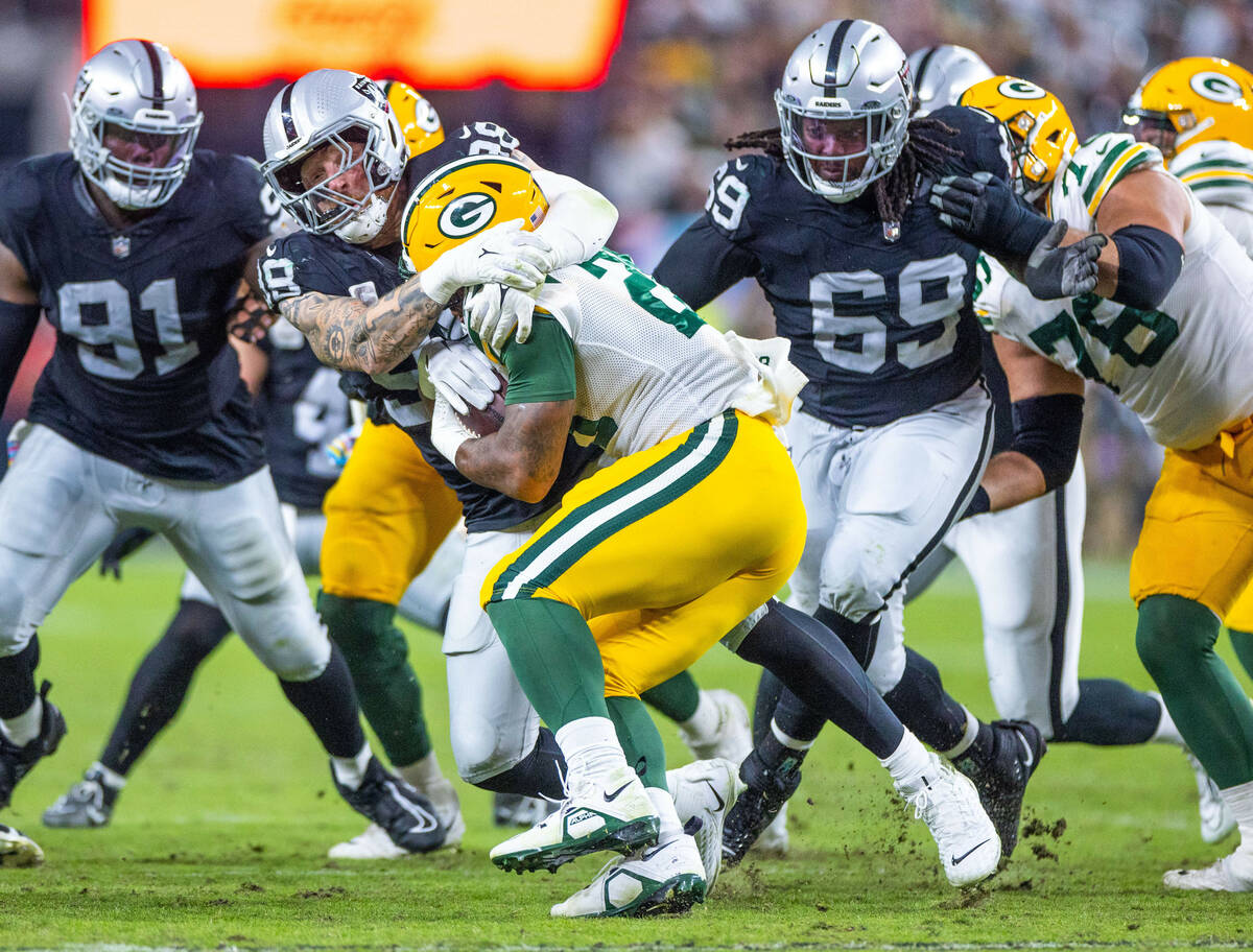 Raiders defensive end Maxx Crosby (98) stops Green Bay Packers running back Patrick Taylor (27) ...