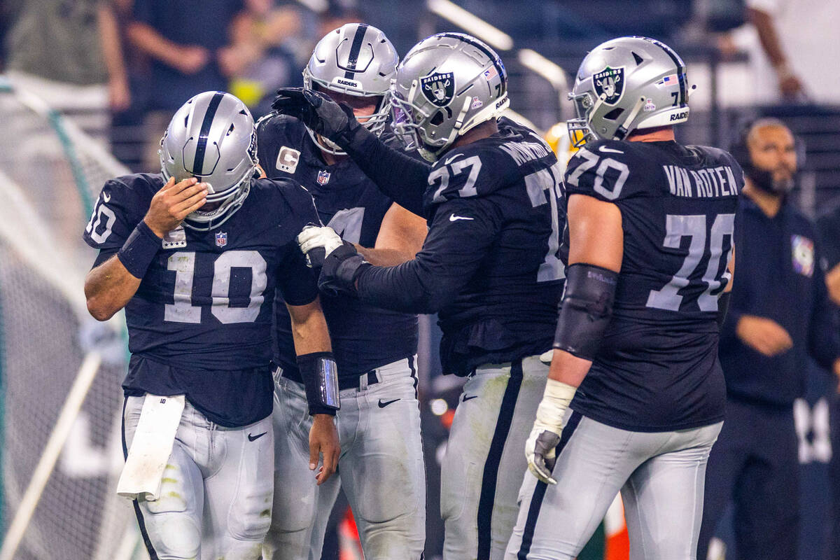 Raiders quarterback Jimmy Garoppolo (10) is checked on by teammates after a hard sack from the ...
