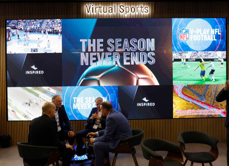 Representatives and potential clients discuss as multiple virtual sports are played on giant sc ...