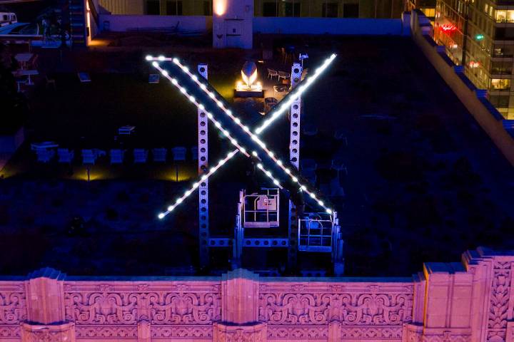 Workers install lighting on an "X" sign atop the company headquarters, formerly known as Twitte ...