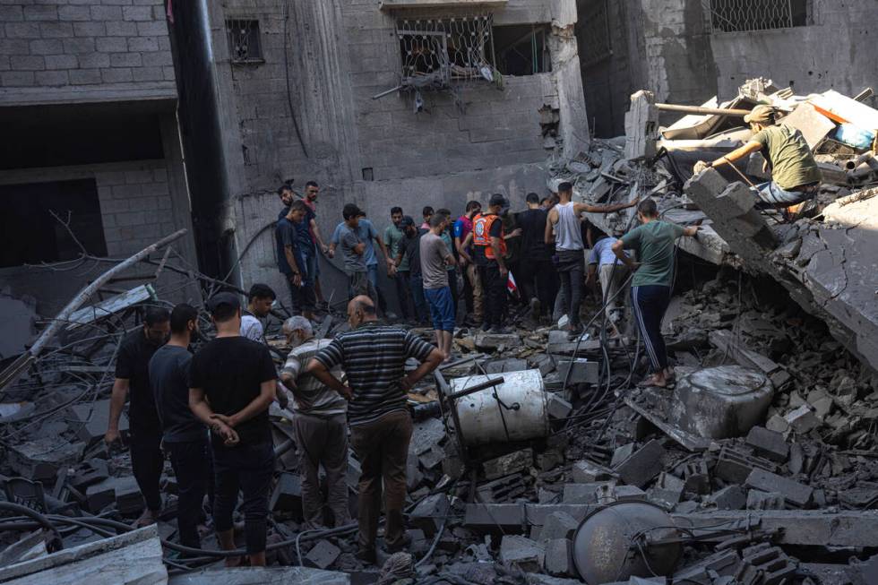 Palestinians search for bodies and survivors in the rubble of a residential building leveled in ...