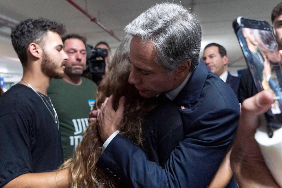 U.S. Secretary of State Antony Blinken is embraced by Lior Gelbaum, right, 24, a dual U.S.-Isra ...