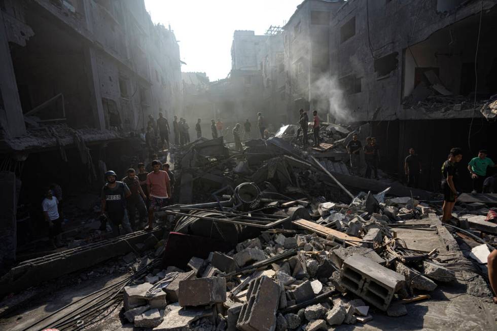 Palestinians search for bodies and survivors in the rubble of a residential building leveled in ...