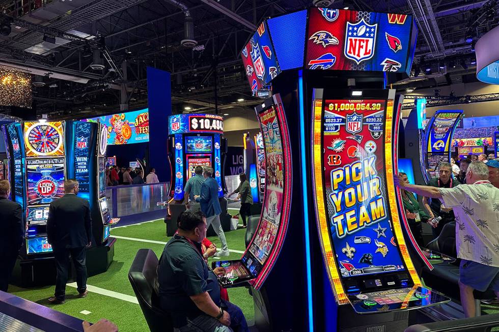 NFL-themed slot machines being played by attendees at Aristocrat Gaming's booth at the Global G ...