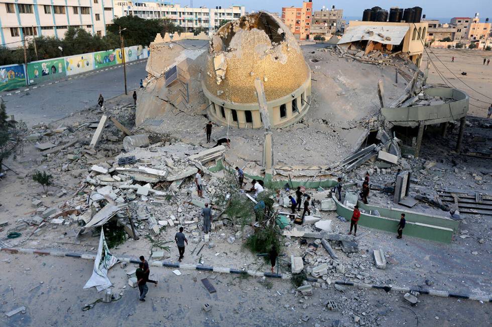 People stand outside a mosque destroyed in an Israeli air strike in Khan Younis, Gaza Strip, Su ...