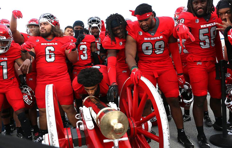 UNLV players celebrate their victory over Nevada by claiming the Fremont Cannon at Mackay Stadi ...