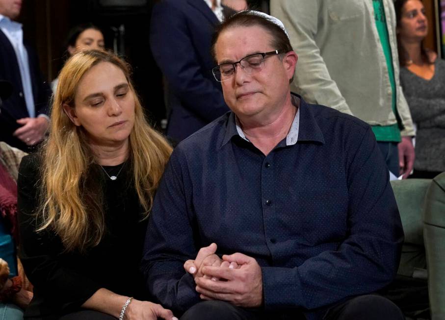 Sigal Zamir, left, and her husband, Avi, hold hands as they attend a prayer vigil for Judith Ra ...