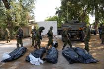 Israeli soldiers stand next to the bodies of Israelis killed by Hamas militants in kibbutz Kfar ...