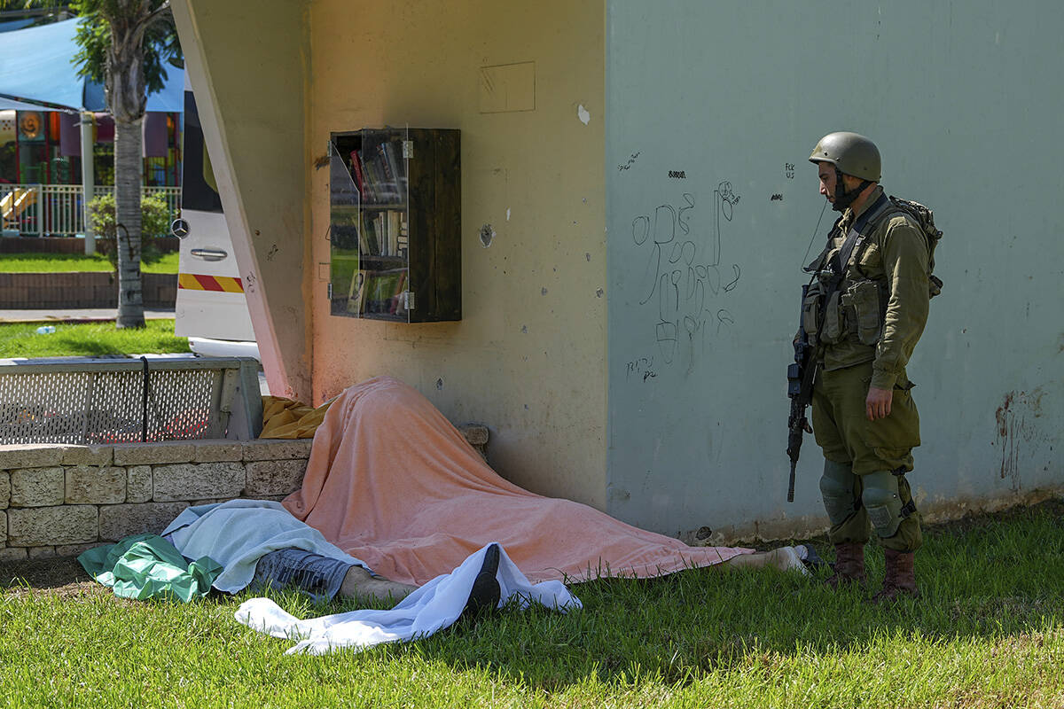 An Israeli soldier stands by the bodies of Israelis killed by Palestinian armed militants who e ...