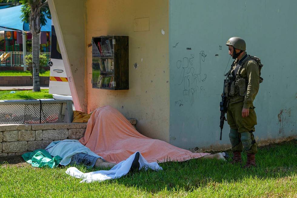 An Israeli soldier stands by the bodies of Israelis killed by Palestinian armed militants who e ...