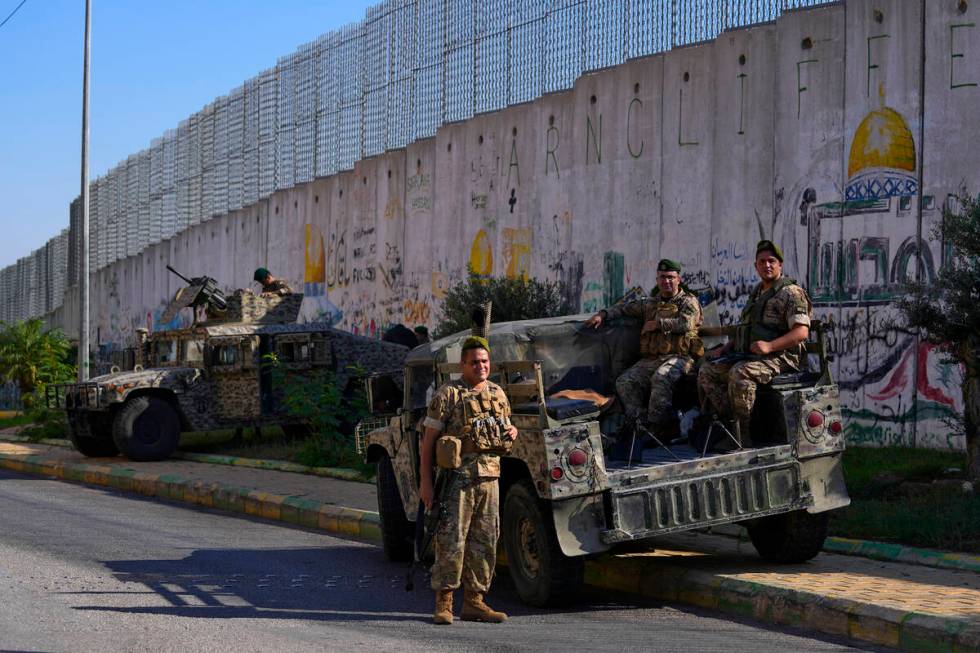 Lebanese army soldiers sit on their armored vehicles next to the wall that separates Lebanon fr ...