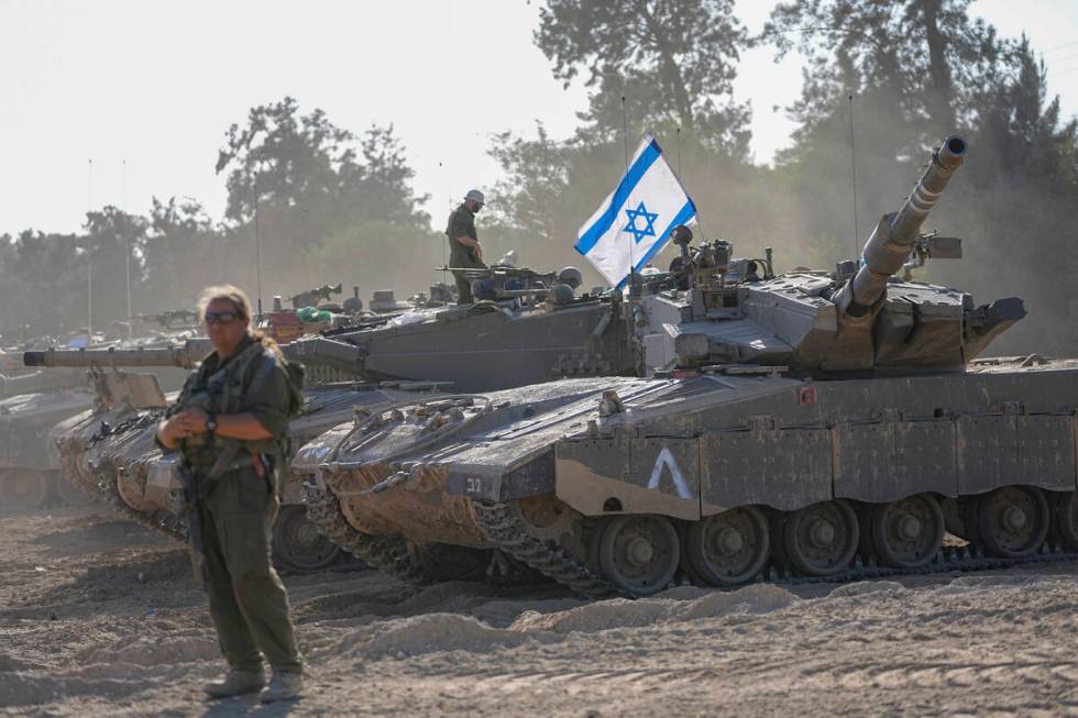 Israeli soldiers work on a tank at a staging area in southern Israel near the border with the G ...