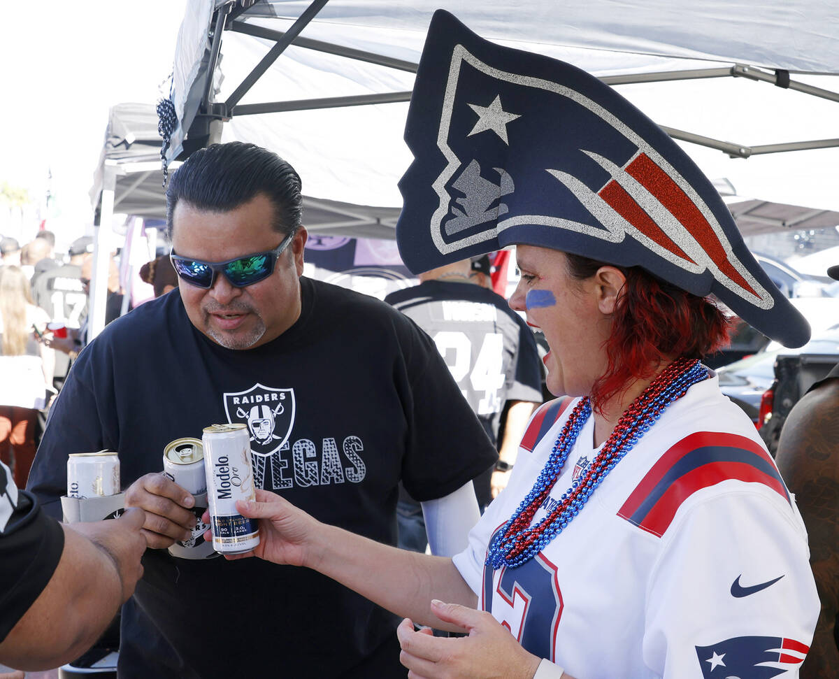 New England Patriots fan Casey Cupples cheers with Raiders fan Edwin Flores at a tailgate outsi ...