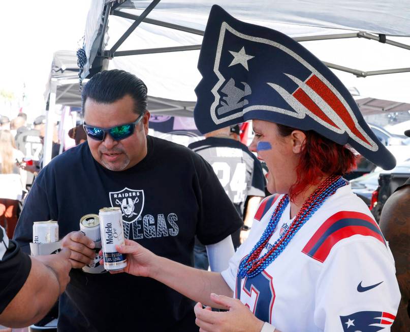 New England Patriots fan Casey Cupples cheers with Raiders fan Edwin Flores at a tailgate outsi ...