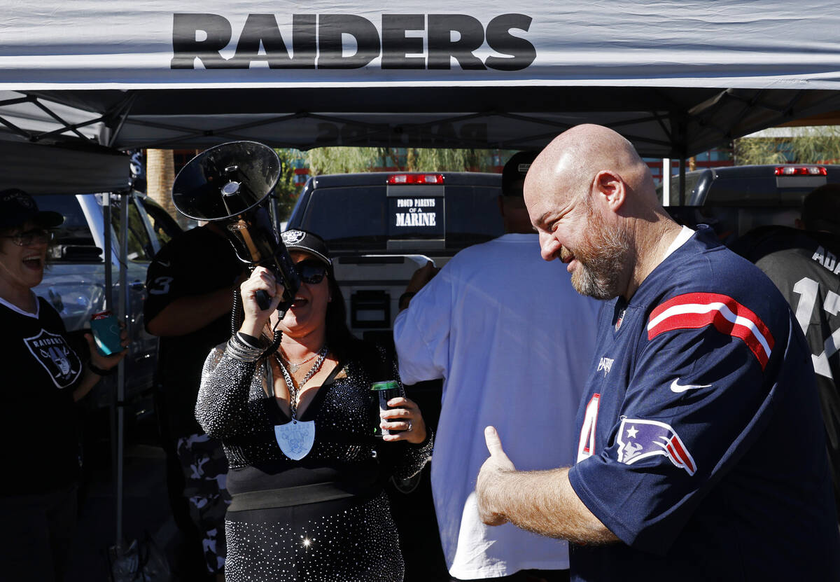 New England Patriots fan RJ Salow flashes a thumbs-up as Raiders fan Tiffany Megaraiderette sho ...