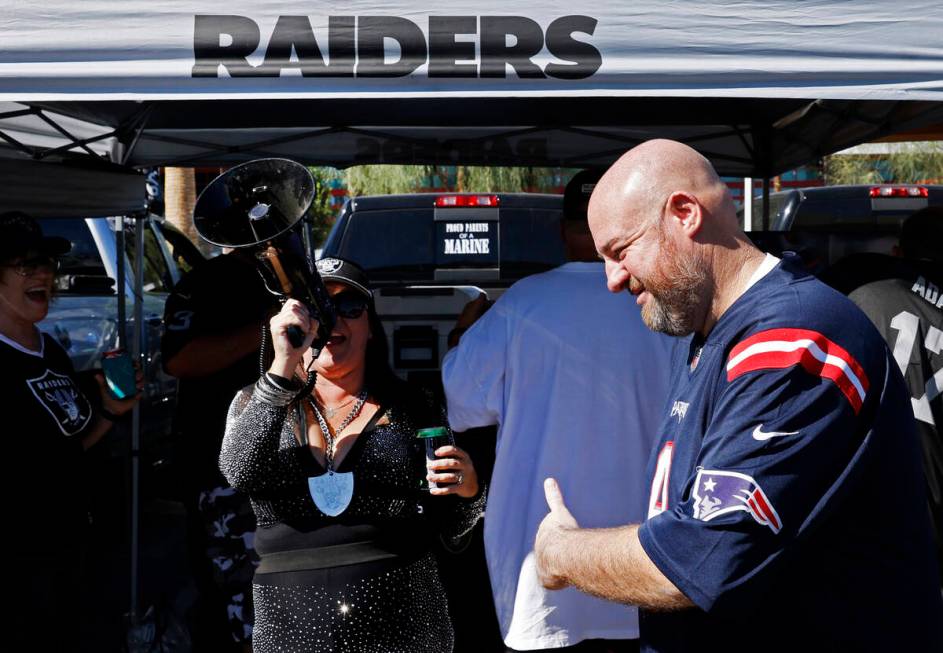 New England Patriots fan RJ Salow flashes a thumbs-up as Raiders fan Tiffany Megaraiderette sho ...