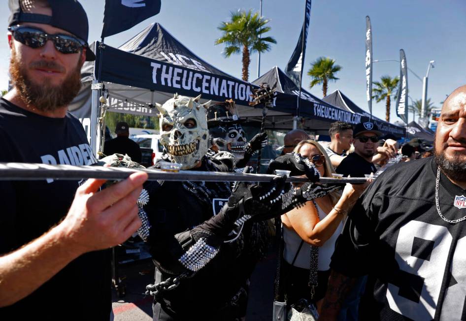 Raiders fans prepare to take a shot at a tailgate outside Allegiant Stadium before the start of ...