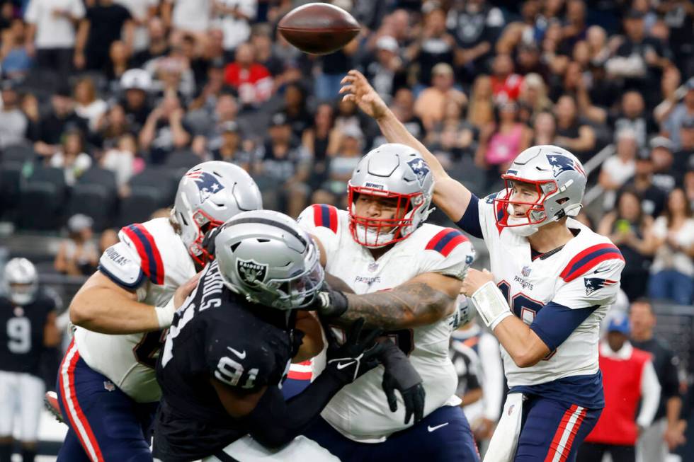 New England Patriots quarterback Mac Jones (10) throws under pressure from Raiders defensive ta ...